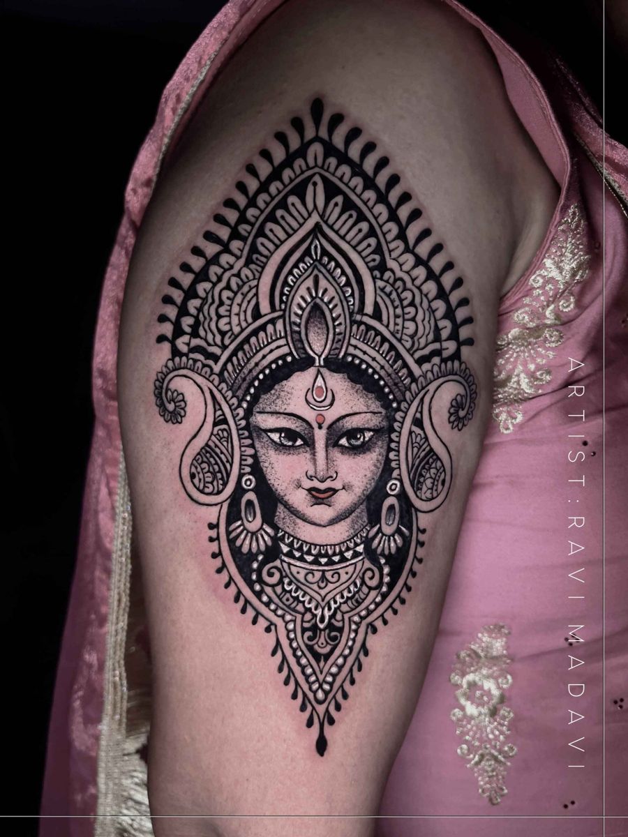 Goddess Durga face framed by an ornamental mandala tattoo on the upper arm